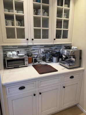 A kitchen with white cabinetry, a coffee machine, and a toaster.