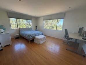 Un dormitorio con cama, escritorio y computadora.