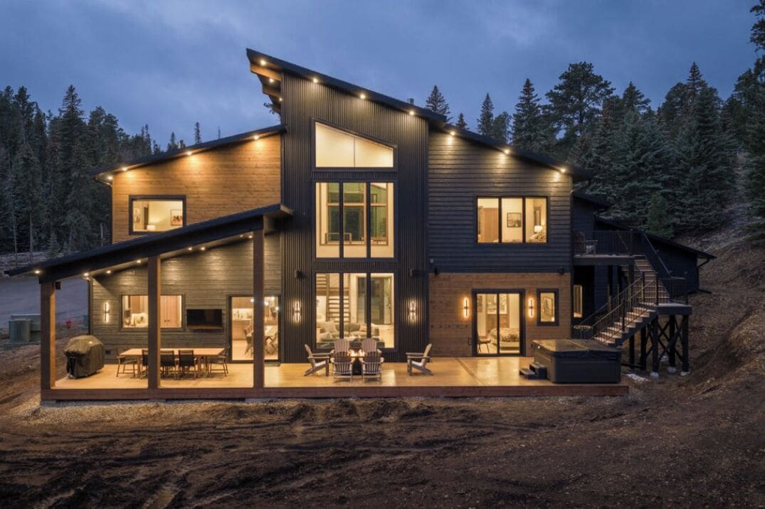 Une maison moderne à deux étages, dotée d’un patio couvert, de grandes fenêtres et d’un escalier menant à un niveau supérieur.