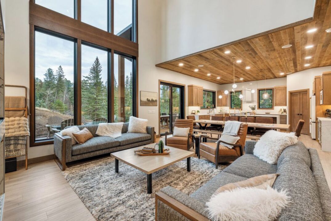 A spacious living area with a large window, a sofa, a coffee table, and a fireplace.