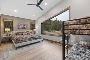 A bedroom with a bed, a desk, a chair, a large window, and a ceiling fan. - Top Shelf Lodge -luxury 6 bedroom 6.5 bathroom AC, Hot Tub, Golf Simulato (Lead)