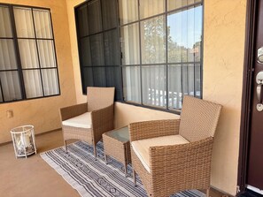 Una habitación con dos sillones de mimbre, un tapete estampado y un ventanal de vidrio.