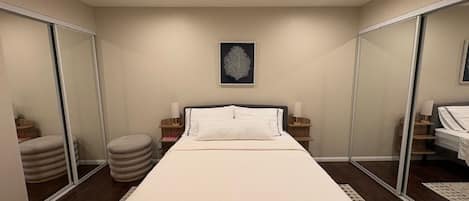 A hotel room with a bed, bedside tables, a mirror, and a framed artwork on the wall.