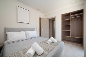 A hotel room with a bed, a wardrobe, and a door leading to another room. - ARIA LUXURY LIVING (ΑΦΑΝΤΟΥ)