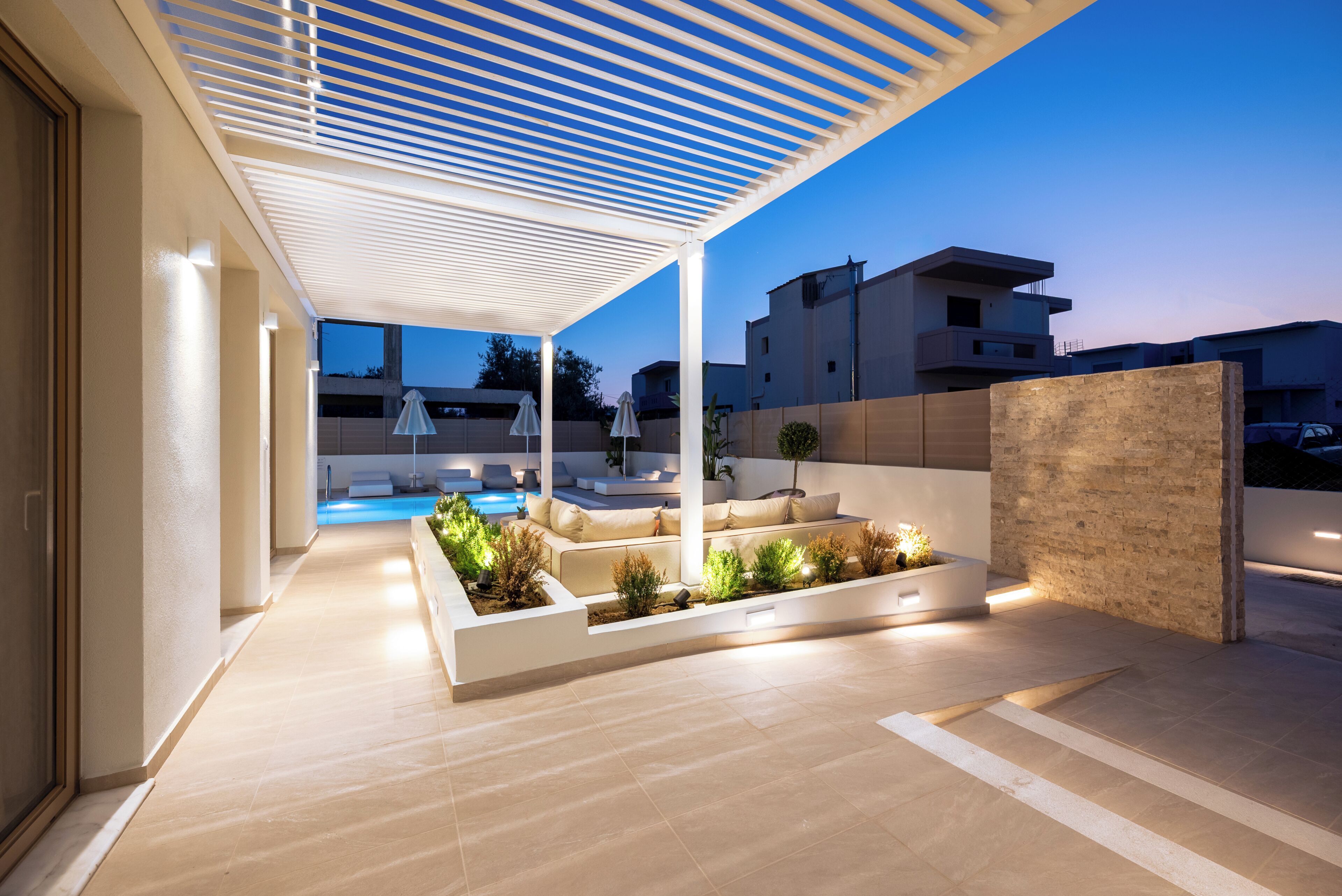 Ett modernt utomhusområde med pool, sittplatser och en pergola.