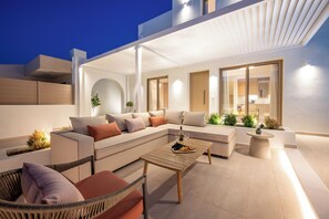 A modern outdoor living space with a sofa, chairs, and a coffee table. - ARIA LUXURY LIVING (ΑΦΑΝΤΟΥ)