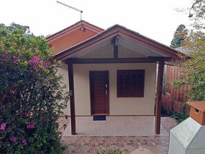 Une maison de plain-pied avec un toit brun, deux portes en bois et un petit porche.