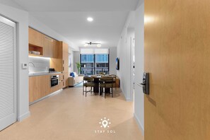 Eine moderne Küche mit Holzausstattung, ein Essbereich mit Tisch und Stühlen und ein Blick auf die Stadt durch große Fenster.