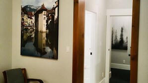 Un pasillo con un marco de puerta de madera, una silla y un cuadro en la pared.
