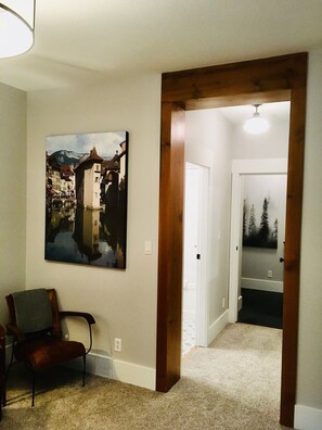 A hallway with a wooden door frame, a chair, and a painting on the wall. - Mountain Getaway – Ski-In / Ski-Out Suite (Kimberley)