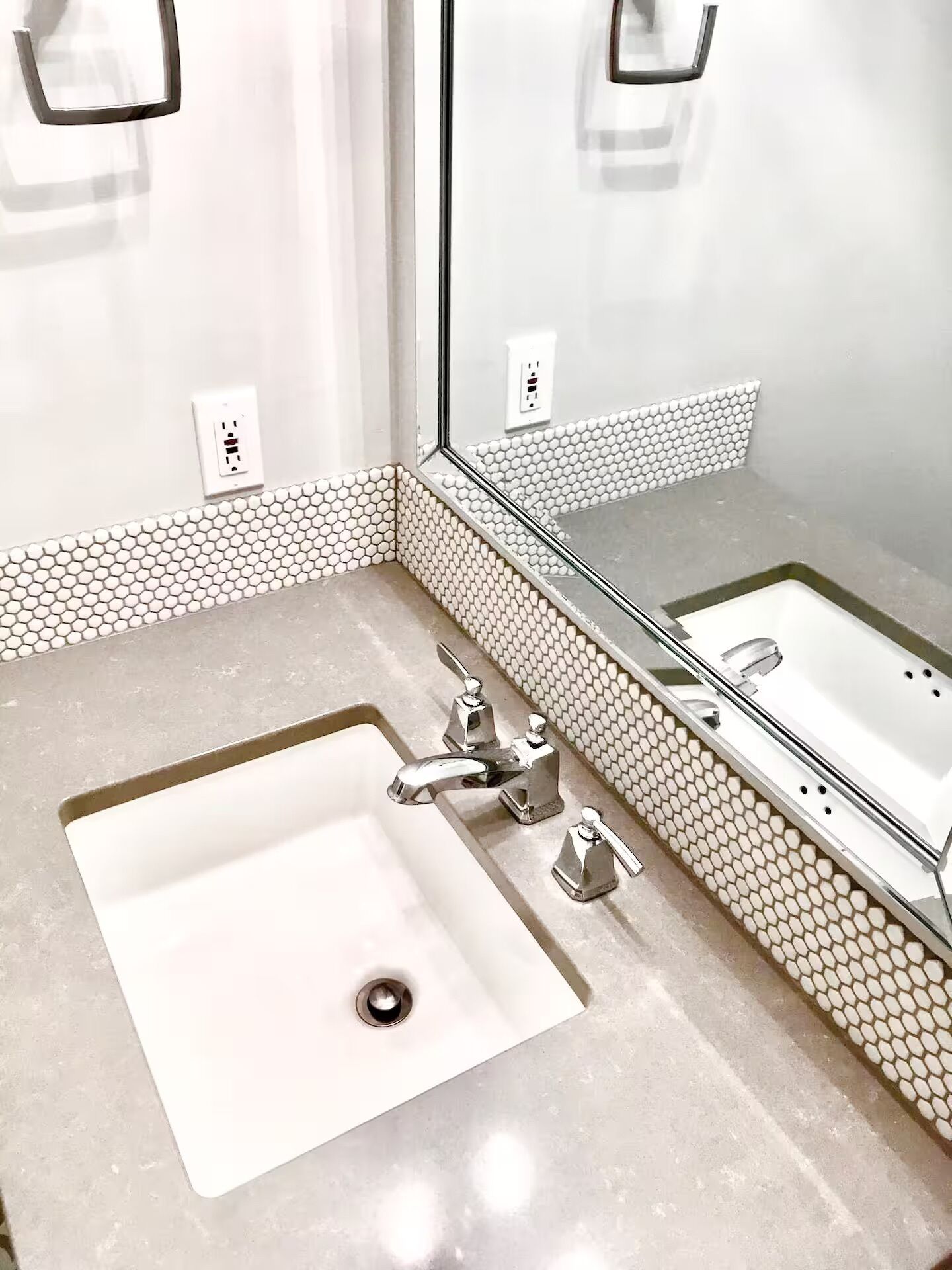 A bathroom with a white sink, a mirror, and a tiled backsplash.