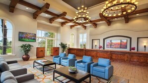 A spacious lobby with a wooden ceiling, blue seating, a reception desk, and artwork on the walls.