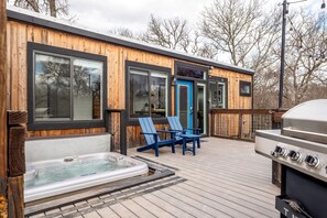 Une terrasse en bois avec un jacuzzi, un coin salon extérieur et un barbecue.