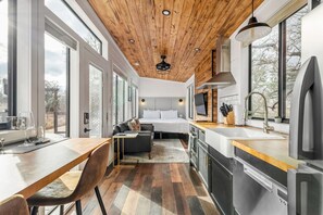 Une cuisine moderne avec un plafond en bois, un coin repas avec une table et des chaises, et une chambre à coucher avec un lit et un téléviseur.