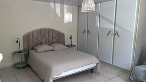 A bedroom with a bed, bedside tables, a wardrobe, and a hanging light fixture. - Cozy house with a private hot tub, 80 m from the ocean, 200 m from downtown, parking available (La Tranche-sur-Mer)