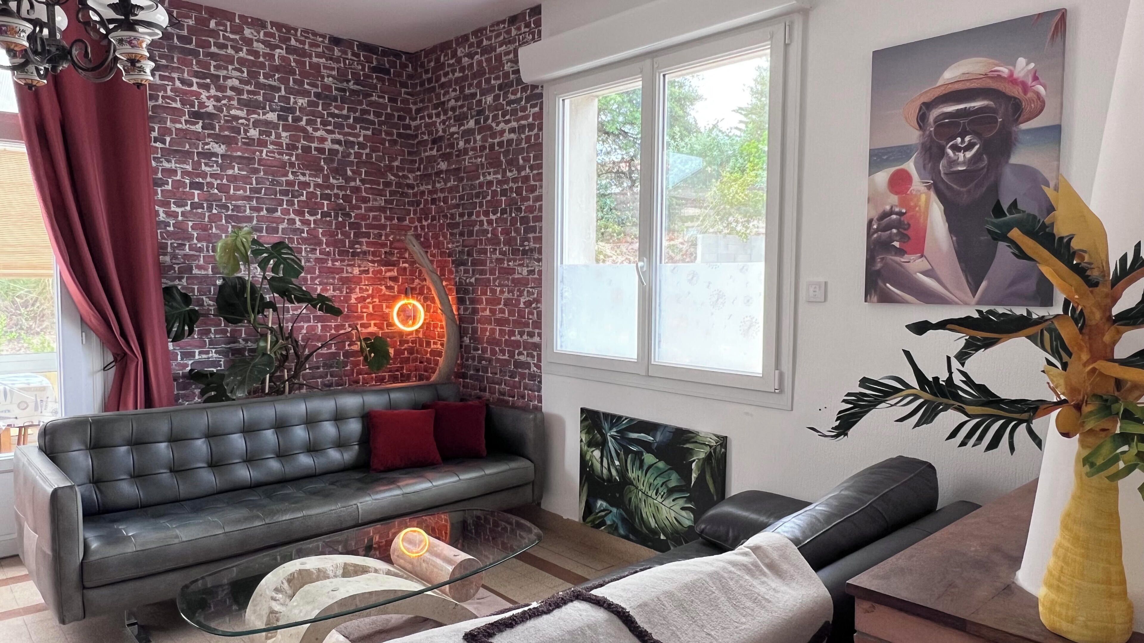 Een woonkamer met een bakstenen muur, een bank, een glazen salontafel en een groot raam.