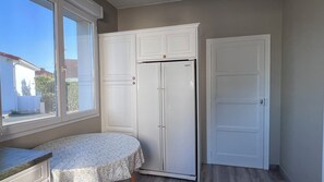 A room with a window, a white cabinet, a white door, and a table with a floral tablecloth. - Cozy house with a private hot tub, 80 m from the ocean, 200 m from downtown, parking available (La Tranche-sur-Mer)