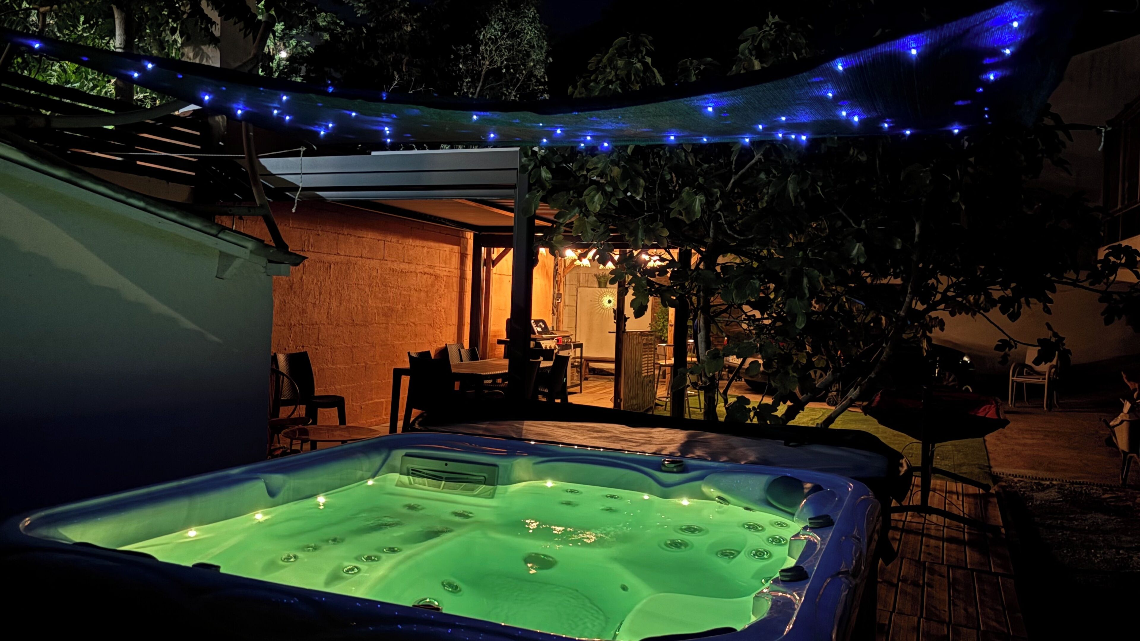 An outdoor hot tub area with a brick wall and a covered seating area.