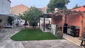 A patio with artificial grass, a pergola, outdoor furniture, and a barbecue area. - Vrbo Property (La Tranche-sur-Mer)