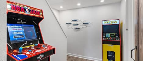 An indoor arcade with two basketball-themed gaming machines, one labeled 'NBA JAM' and the other 'PAC-MAN'.