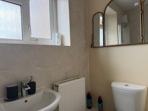 A bathroom with a white sink, a mirror, a toilet, and a window. - White Oak Studio Hideaway (London)