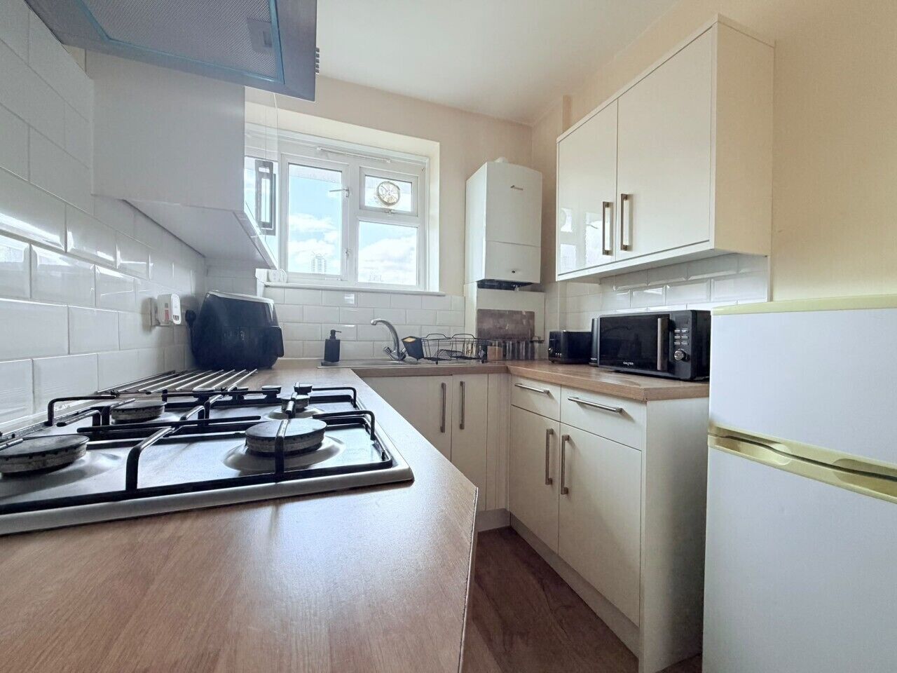 A kitchen with a gas stove, microwave, and white cabinets.