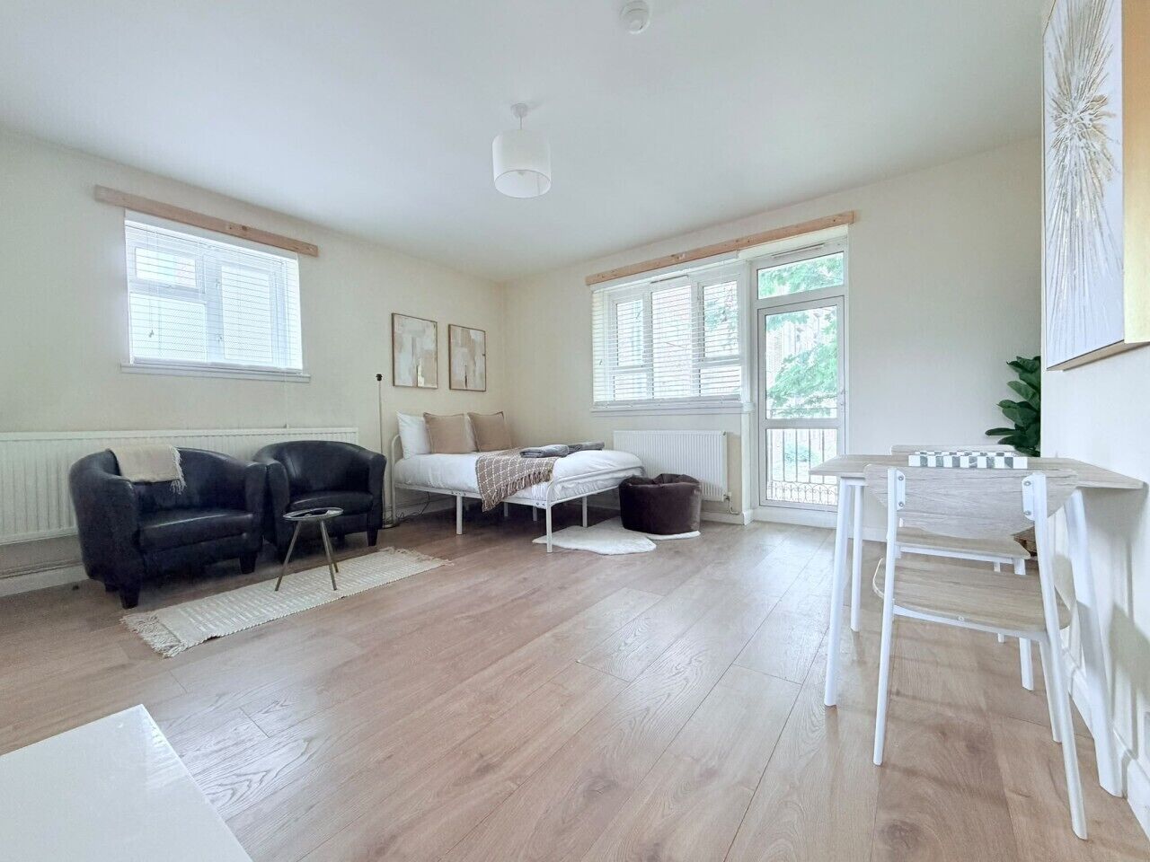 A room with a bed, a sofa, a dining table, and a chair.