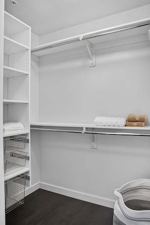 A walk-in closet with open shelves, a metal rack, and a dark floor. - Casa Positano® Designer 2BR/2BA in Irvine w/ Pool (Irvine)
