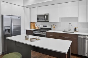 A modern kitchen with stainless steel appliances, a central island, and a dishwasher. - Casa Positano® Designer 2BR/2BA in Irvine w/ Pool (Irvine)