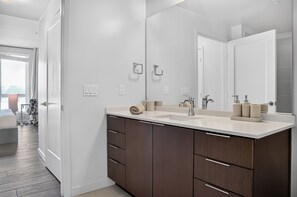 A modern bathroom with a large mirror, two sinks, and dark wooden cabinets. - Casa Positano® Designer 2BR/2BA in Irvine w/ Pool (Irvine)