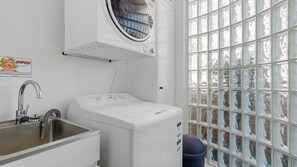A laundry room with a washing machine, a sink, and a window with a view. - Beach Lane | 250m to the beach | Accom Holidays (TERRIGAL)