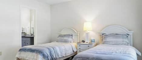 Ein Schlafzimmer mit zwei Betten, einem Deckenventilator und einem Nachttisch mit Lampe.