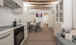 A modern kitchen with a dining area, a flat-screen TV, and a cozy seating area. - Domo de Mesu—House Live Express (Cagliari)