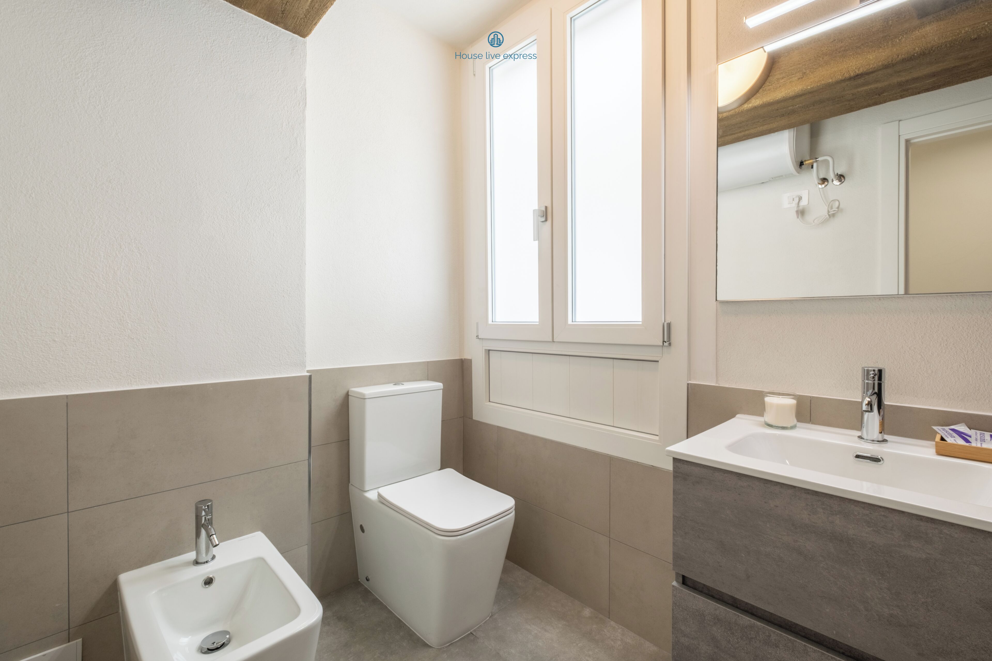 A modern bathroom with a toilet, sink, and mirror.