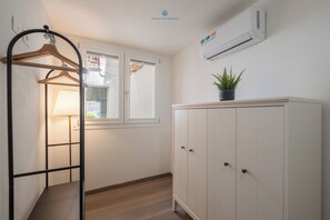 Une chambre équipée d’une armoire, d’un portant, d’une fenêtre et d’un climatiseur.