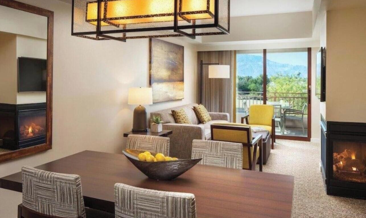 Une chambre d’hôtel comprenant un coin repas, un ensemble de canapés, une cheminée et une vue sur l’extérieur.