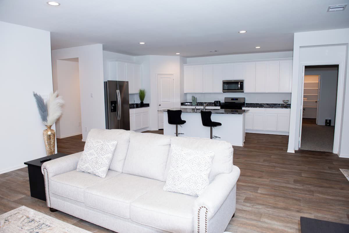 A modern kitchen with white cabinets, stainless steel appliances, and a central island with bar stools.