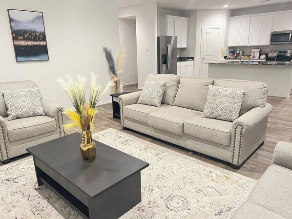 A modern living room with a sofa, coffee table, and decorative vase. - 5BR All One Level | Fenced Yard | Pet Friendly (Richmond)