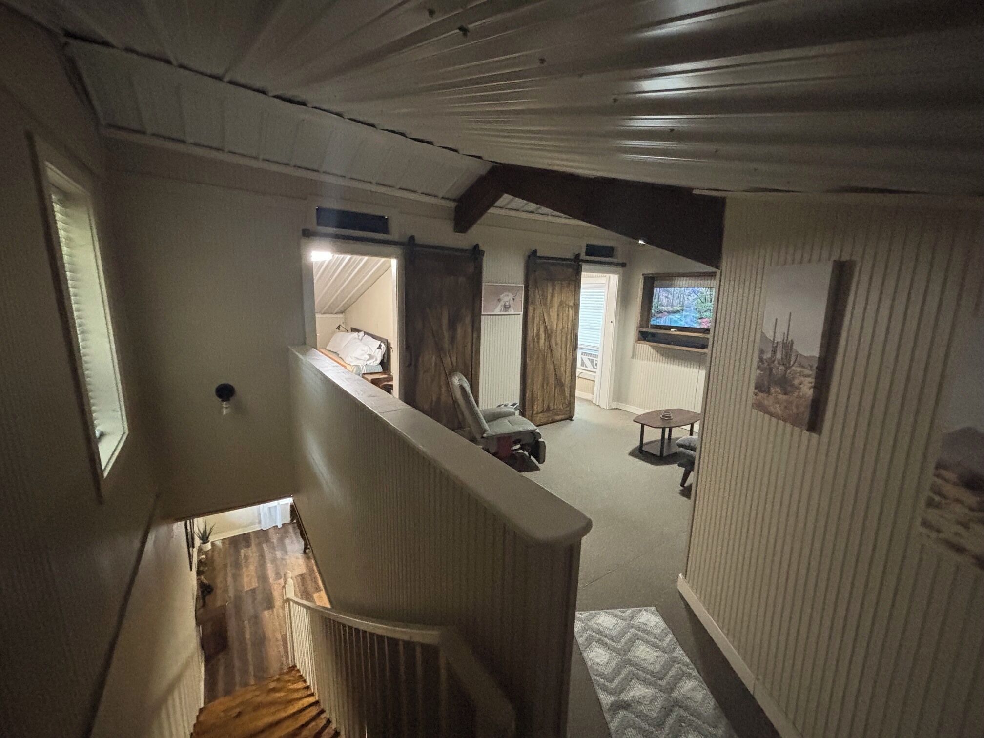 Un corridoio stretto con una scala in legno che conduce a una stanza con un letto e una finestra.
