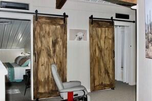 Una habitación con una cama, una silla y dos puertas correderas tipo granero.