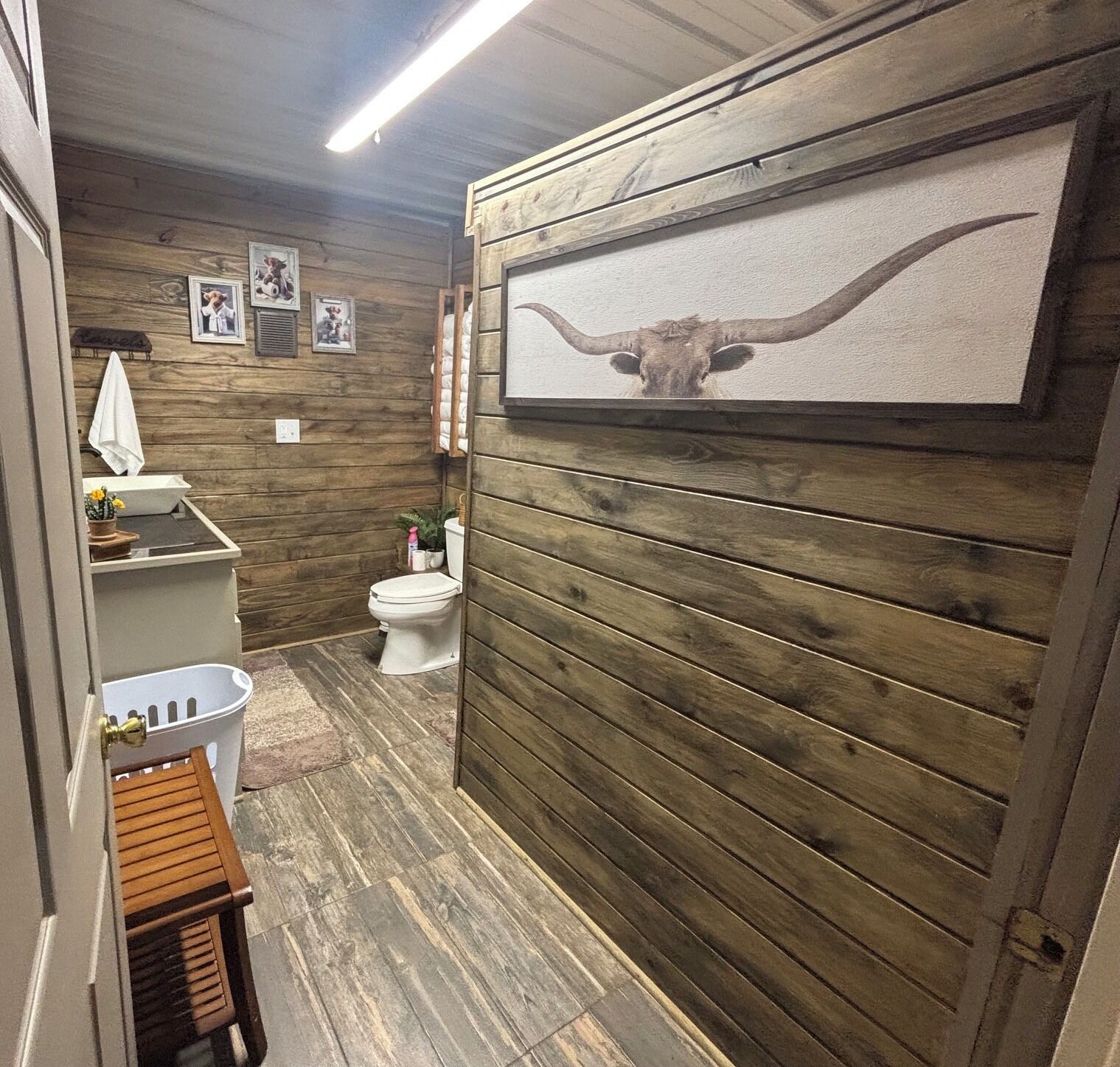 Un baño con paneles de madera, un inodoro, un lavabo y una zona de ducha.