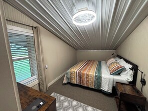 Un dormitorio pequeño con una cama individual, un escritorio y una ventana con persianas.