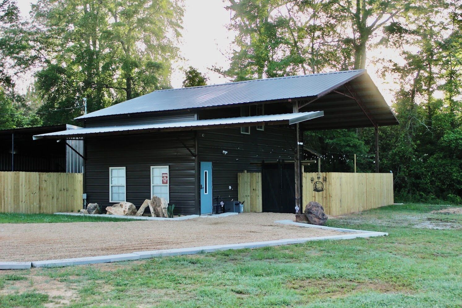 A single-story building with a covered porch, a blue door, and a wooden fence.