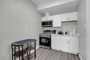 A compact kitchen with white cabinets, a microwave, a stove, and a small bar area with stools. - Signature Studio • Free Parking, Pool & Breakfast (Oshawa)