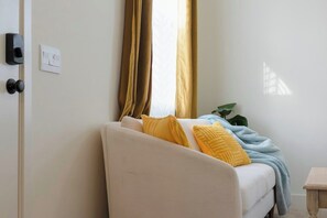 A room with a white sofa, a small wooden table, and a plant.