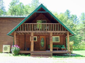 A log cabin with a balcony, a porch, and a front door.