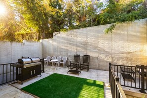 Un jardin avec un barbecue, des meubles d’extérieur et un mur en briques.