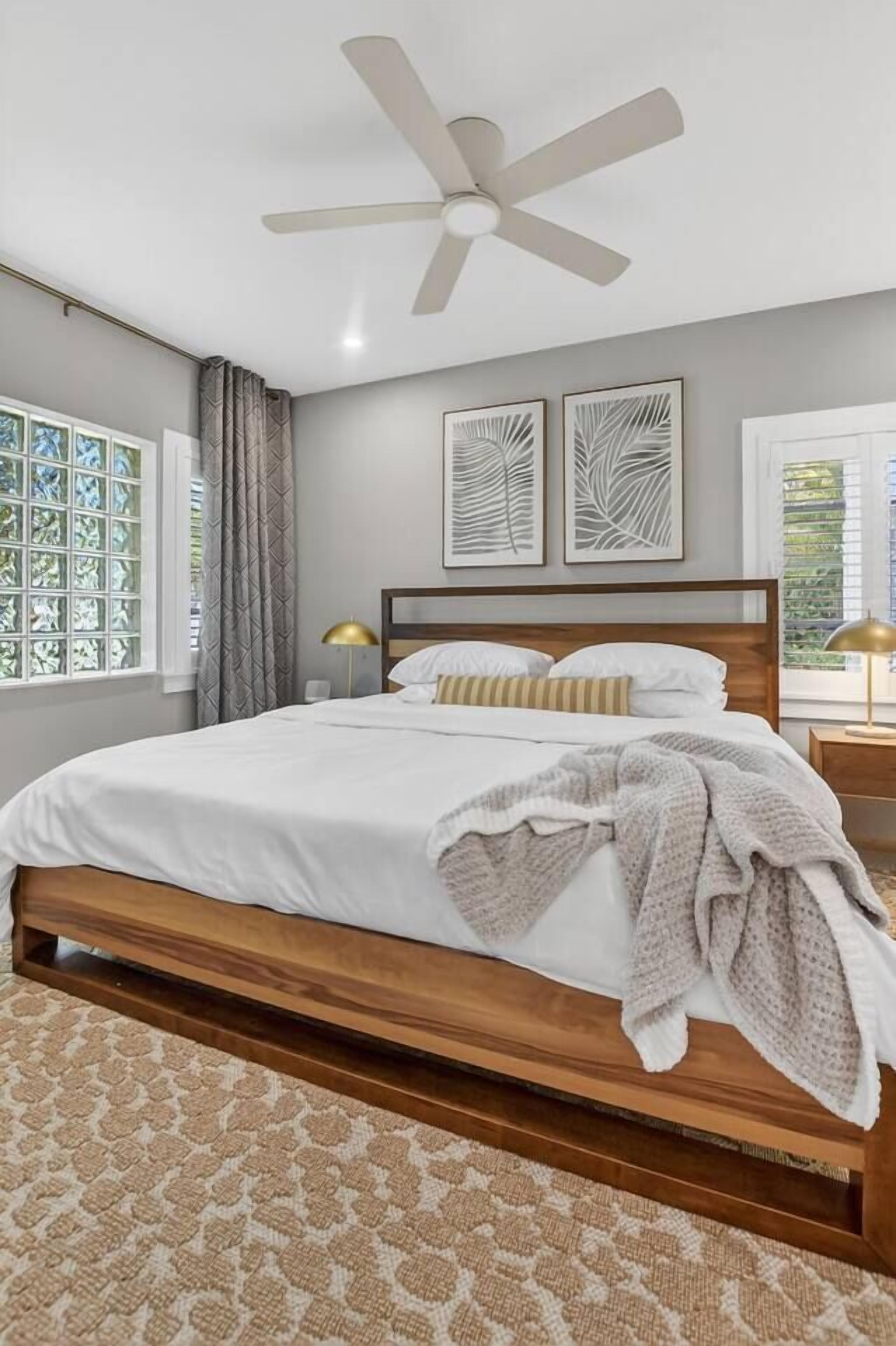 A bedroom with a bed, a ceiling fan, and artwork on the wall.