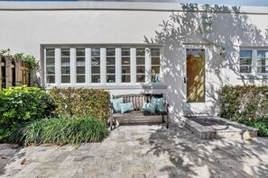 Ein modernes Gebäude mit großen Fenstern, einer Bank mit Kissen und einem gepflegten Garten.