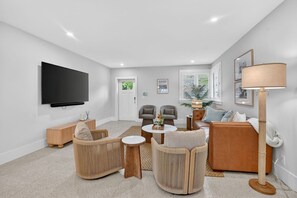 Ein modernes Wohnzimmer mit Flachbildfernseher, Sofas, Couchtisch und Stehlampe.